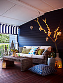 Wicker coffee table and sofa against blue-painted wooden wall on veranda