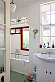 View through open door into white-tiled bathroom with pendant lamp and Art Nouveau architectural elements