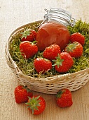 Strawberry jam and fresh strawberries in a basket of moss