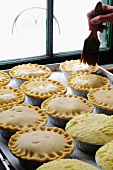 Raw meat pies being brushed