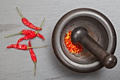 Dried rawit chilli peppers (Indian) being ground in a mortar