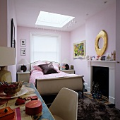 Partially visible dressing table in front of sleigh bed and open fireplace in traditional bedroom painted pastel lilac