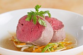 Poached fillet steak on a bed of vegetables with broth