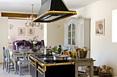 Open-plan interior with free-standing, stylised antique-effect cooker and dining area with dresser in background