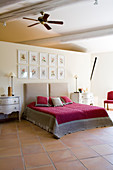 Sammlung gerahmter Bilder an der Wand zum Bad Ensuite über elegantem Doppelbett mit rotem Samtüberwurf