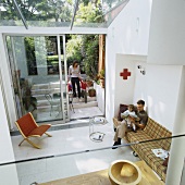 Family in contemporary house - view from above down onto couch and classic side table in minimalist living room with access to garden