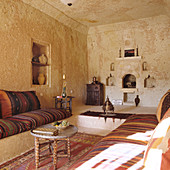 Marokkanischer Wohnraum mit gestreiften Polstern auf gemauerten Podesten und Beistelltisch aus geschnitztem Holz