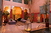 Candle-lit atmosphere in Moroccan courtyard with walls in various shades of red