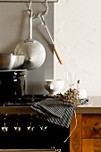 A kitchen counter with a cooker, pots and dried herbs