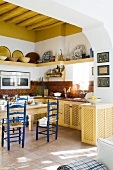 Breiter Durchgang mit Blick in die Küche und auf Essplatz mit blau lackierten Stühlen