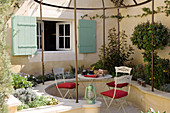 Terrace with curved stone bench and pergola in front of a home