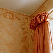 Corner of room with ornate motifs on wall and curtain