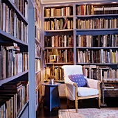 Upholstered antique armchair and side table in corner of library