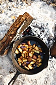Roasted Potatoes Being Cooked in a Cast Iron Skillet Over an Open Fire