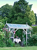 Blick in Gewächshaus auf gedeckten Tisch im Garten