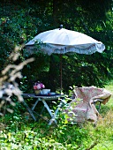 Seating area with vintage parasol in dappled shade in garden