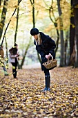 Two women collecting mushrooms in an autumnal forest