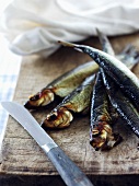 Smoked herring on a wooden board with a knife