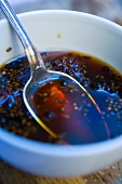 Balsamic dressing with spices in a bowl with a spoon