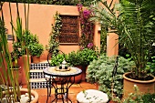 Üppig bepflanzte Terrasse mit rundem Gartentisch (Marokko)