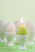 Ostereier und Eierkerze in Eierbechern