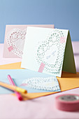 An invitation card decorated with hearts made from doilies