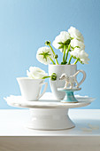 Buttercups in a cup being used as a vase on a cake stand decorated with a doily