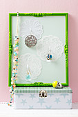 A jewellery holder made from a picture frame and doilies