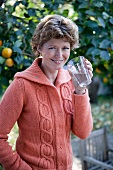 A woman drinking a glass of water in a garden