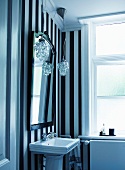 Washstand against black and white striped wall paper in vintage bathroom