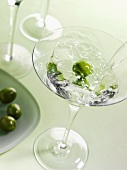 Martini in Glas mit Oliven einschenken
