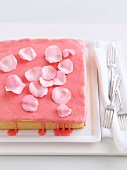 Sponge cake with strawberry icing and rose petals
