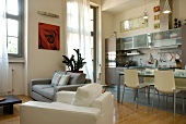 Armchairs upholstered in white and grey in front of dining area and modern fitted kitchen