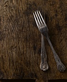 Two old forks on a wooden surface
