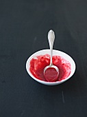 A bowl of raspberry sauce with a spoon