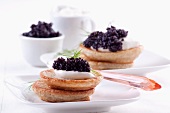 Blinis topped with sour cream and caviar
