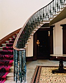 Geschwungener Treppenaufgang mit modernem Teppichläufer in traditionellem Vorraum