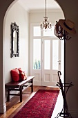 Straw hat on traditional coat rack and view of front door through archway