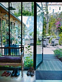 Shoes next to delicate wooden bench and open terrace door with view of garden