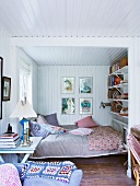Comfortable bedroom with white wood panelling on walls and ceiling
