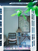 View through terrace door of wicker armchair and rustic table