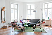 Loungeecke mit Bogenlampe und verschiedenen Sitzmöbeln im Erker eines herrschaftlichen Wohnzimmers mit minimalistischem Flair