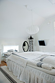 Helles Schlafzimmer in skandinavischem Stil unter dem Dach mit kugelförmiger Hängelampe über Bett
