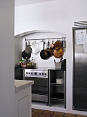 Moderner Küchenofen in Nische und an Haken hängendes Kochgeschirr