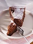 A slice of chocolate cake with icing sugar