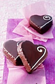 Three heart-shaped chocolates on purple paper