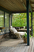 Lounger with fur blanket in pleasant seating area on veranda of summer house in garden