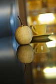 A nashi pear on a mirrored table
