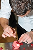 A chef decorating a raspberry tart with a rose petal