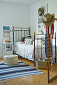 Metallbett im Vintagestil und gestreifter Teppichläufer auf Holzboden in ländlichem Schlafzimmer mit amerikanischem Flair